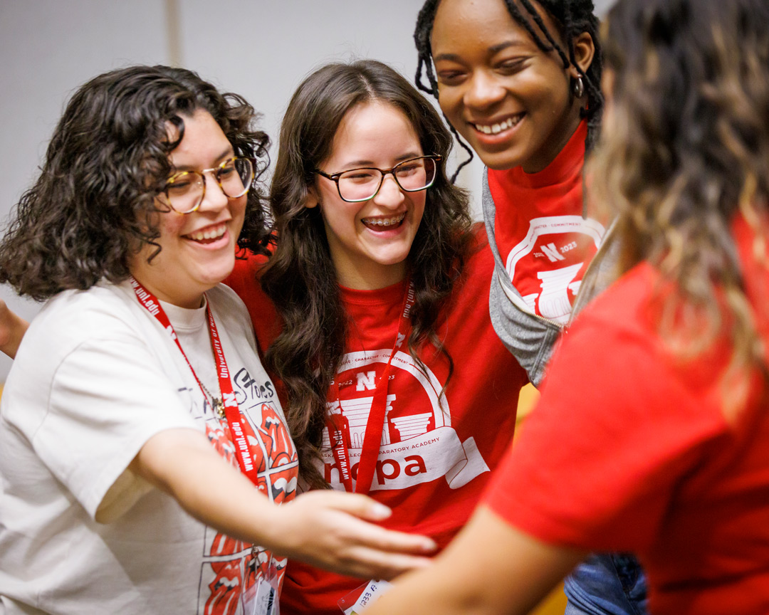 A group of NCPA students huddled together smiling and laughing