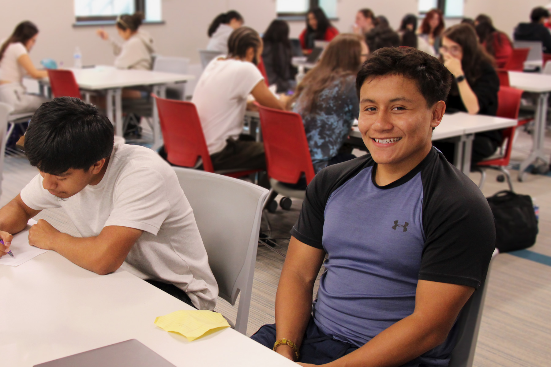 NCPA Student sitting at a desk in a classroom surrounded by other students