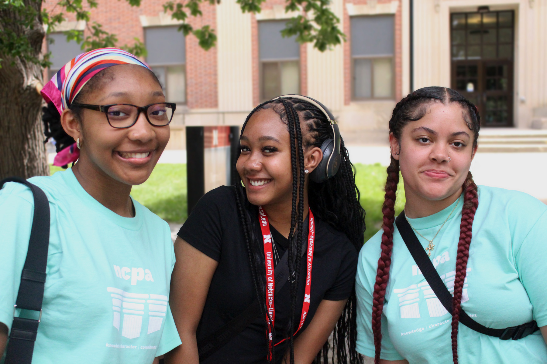 Three students standing outside posing for their picture