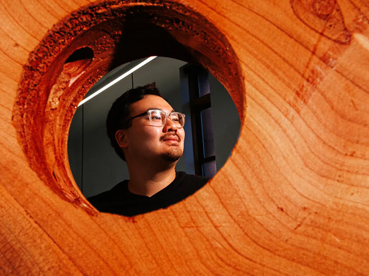 Headshot of Chris Nguyen through hole in wood.