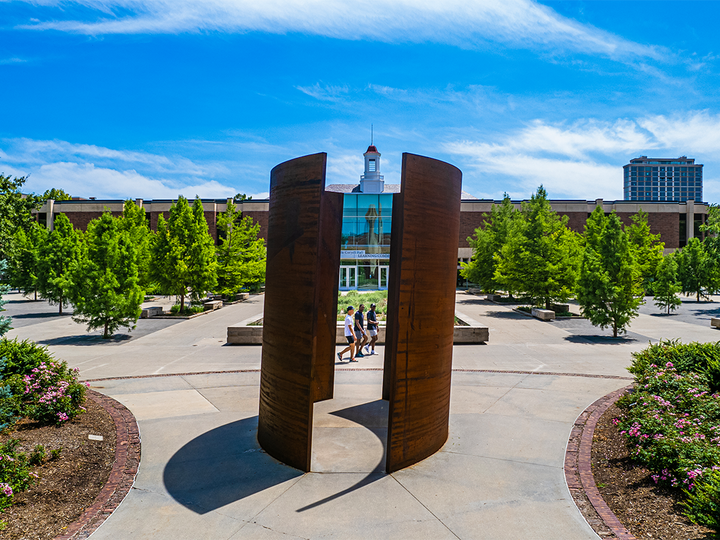 Shot of people walking between sculpture and Love Library.