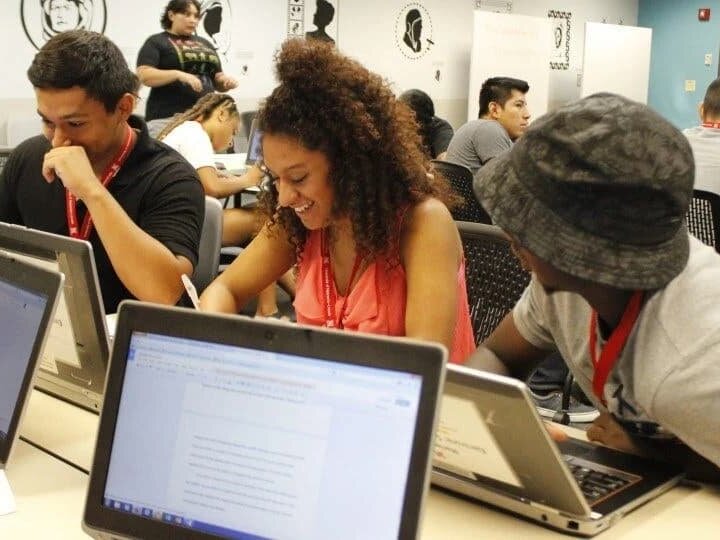 Students working on laptops in classroom.